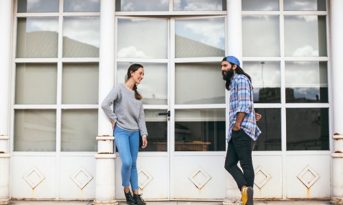lifestyle image of two people talking outside of a building