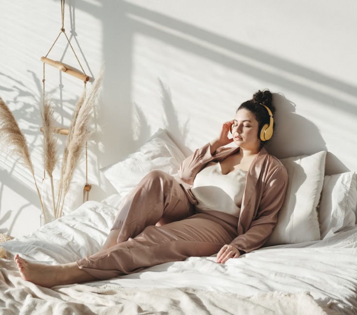 lifestyle image of a young woman laying on a bright bed